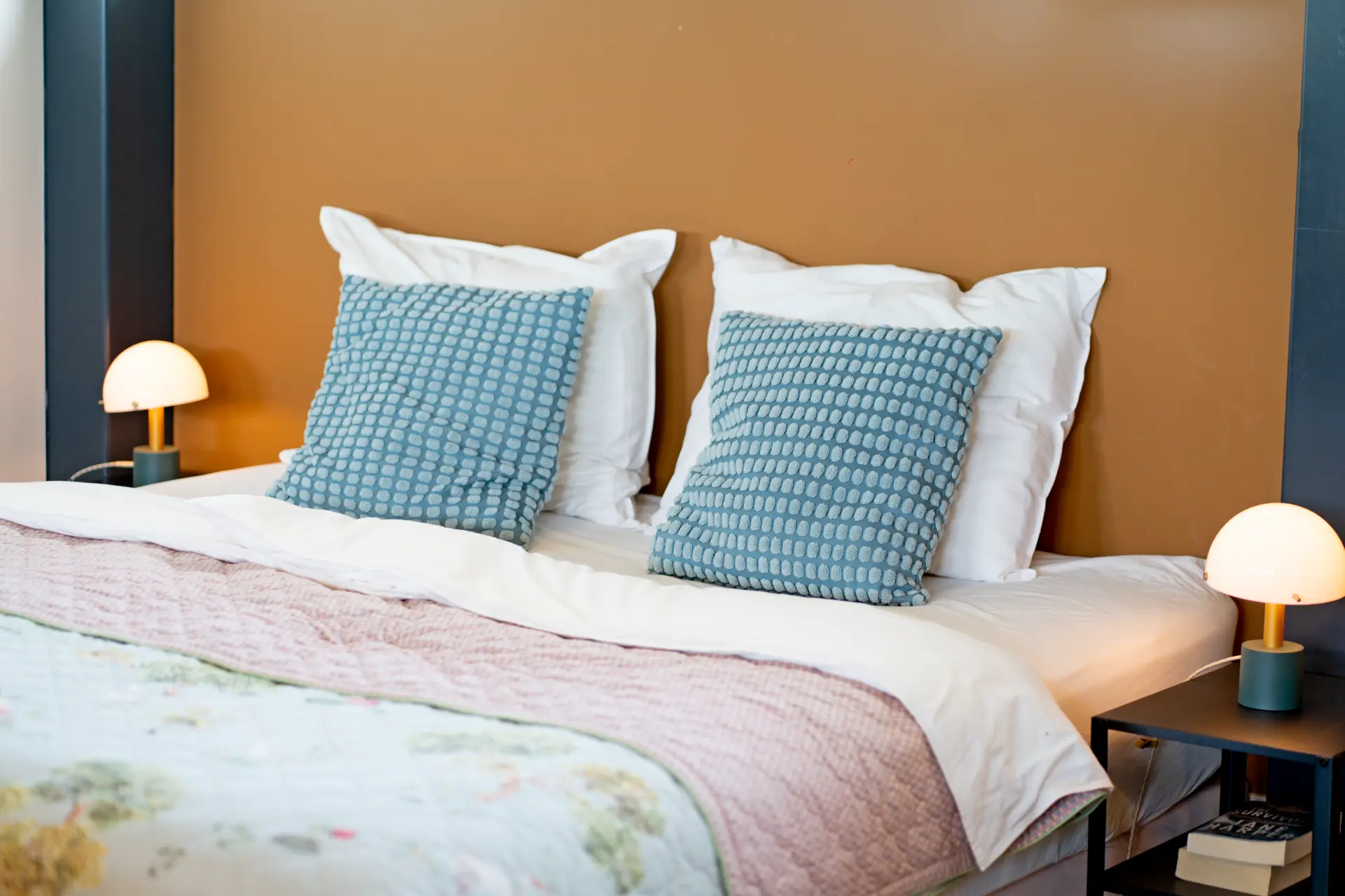 The bed with duck-egg blue cushions and small mushroom lamps