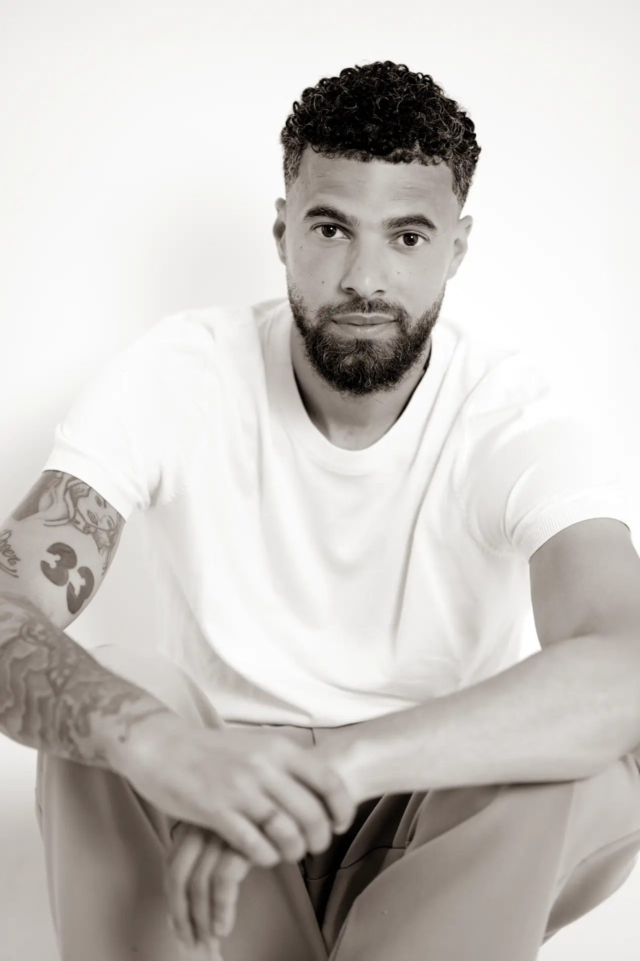 Portrait of a man in a white t-shirt against a bright white studio wall