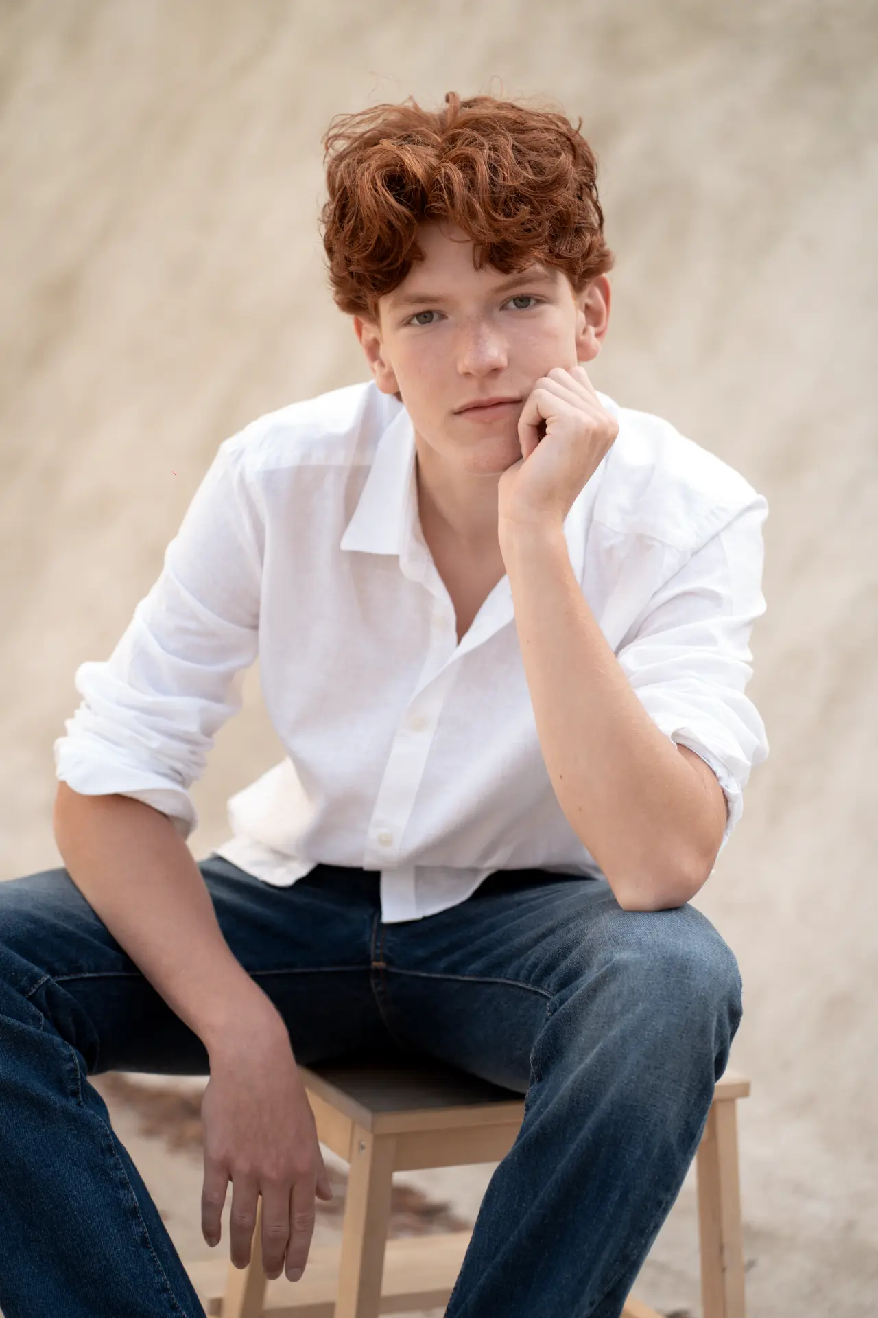 Close seated portrait of Shey against a warm neutral wall