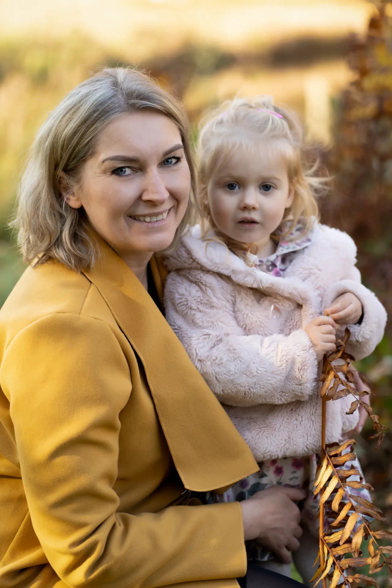 Warm portrait of mother and daughter among autumn foliage