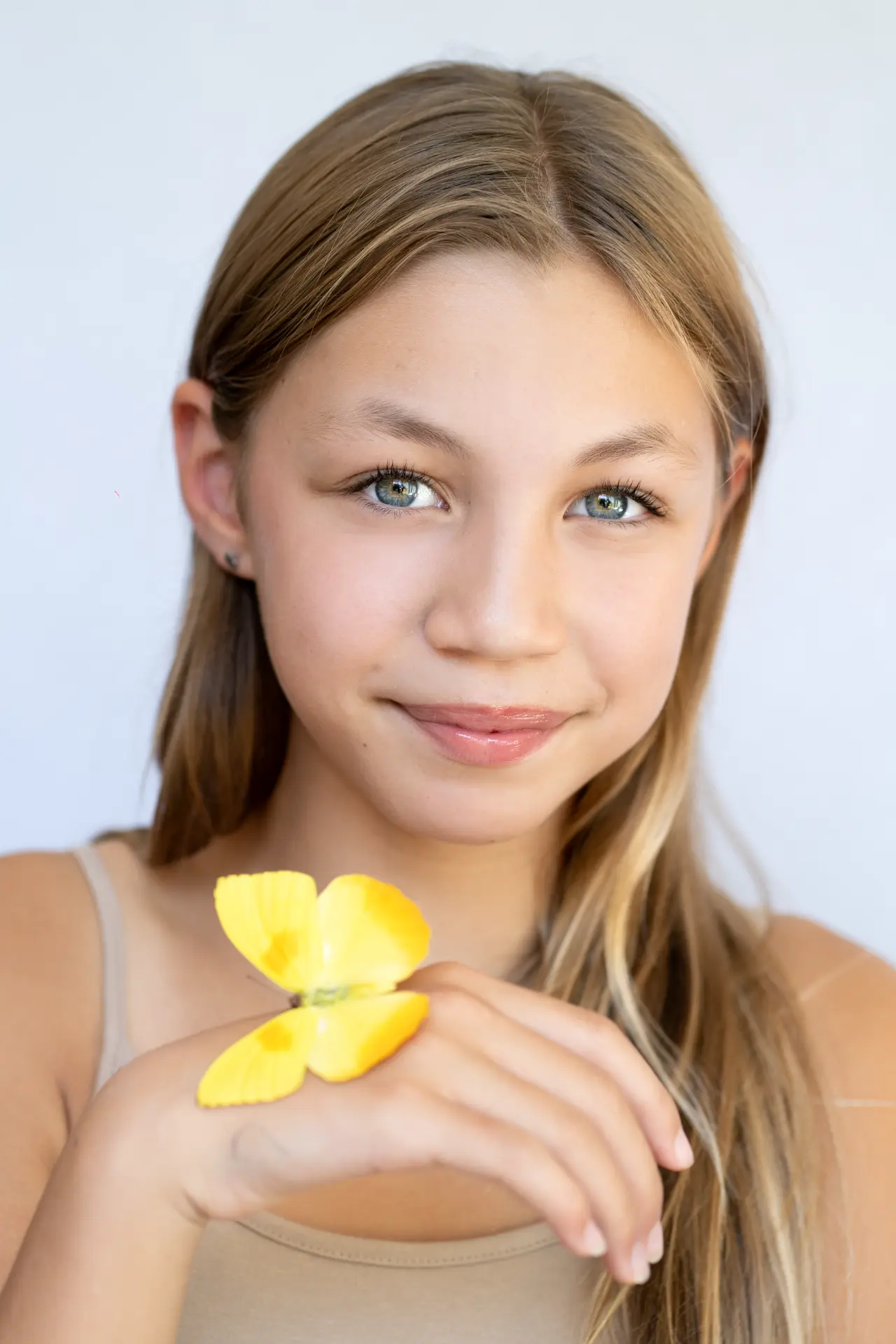 Girl smiling at the camera with a yellow butterfly resting on her wrist